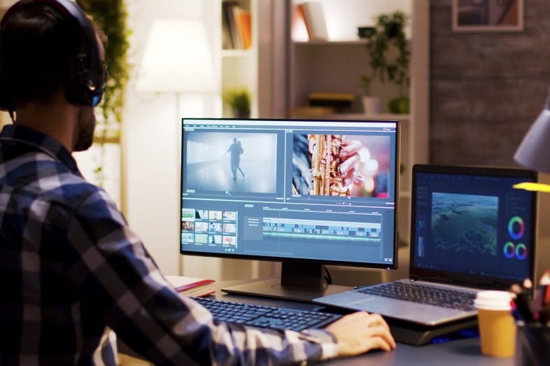 En mann foran en PC skjerm som redigerer video