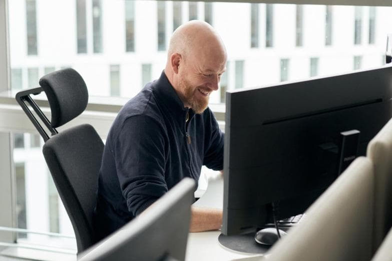 Blid mann sitter foran PC