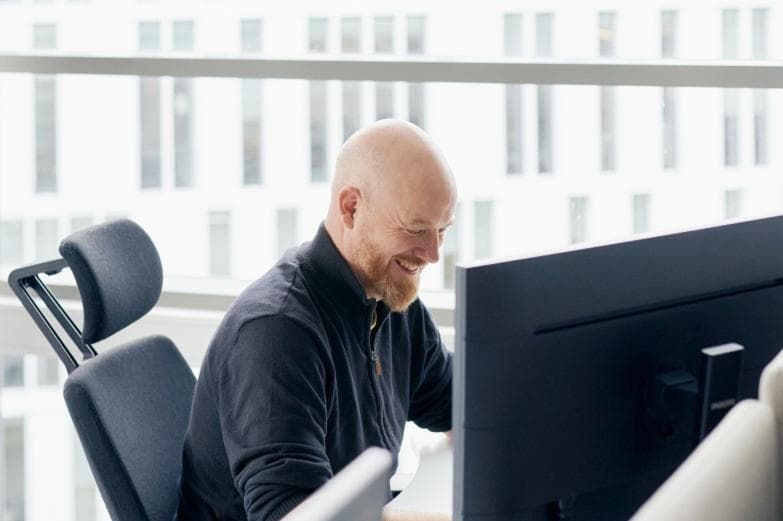 Mann foran PC i kontorlandskap