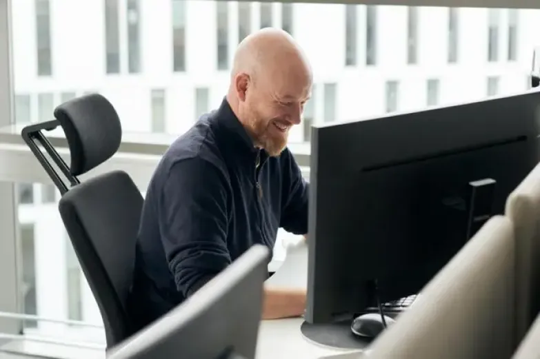 Blid mann som sitter foran PC-en