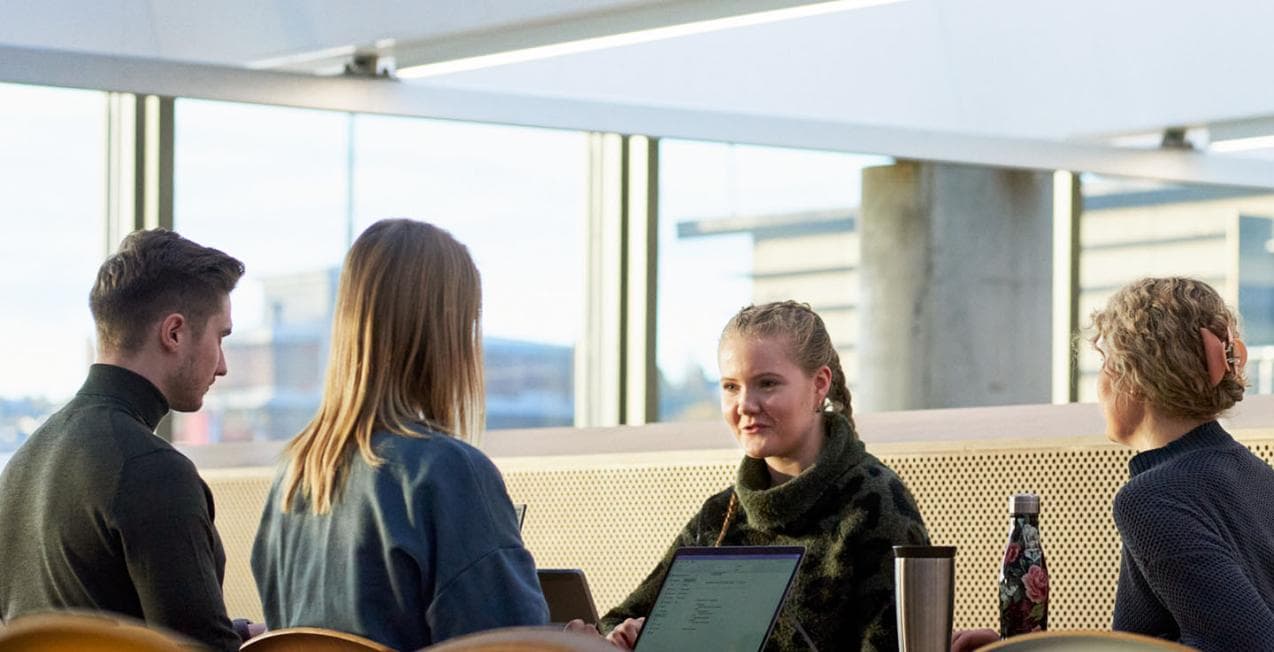 Fire studenter som sitter rundt et bord.