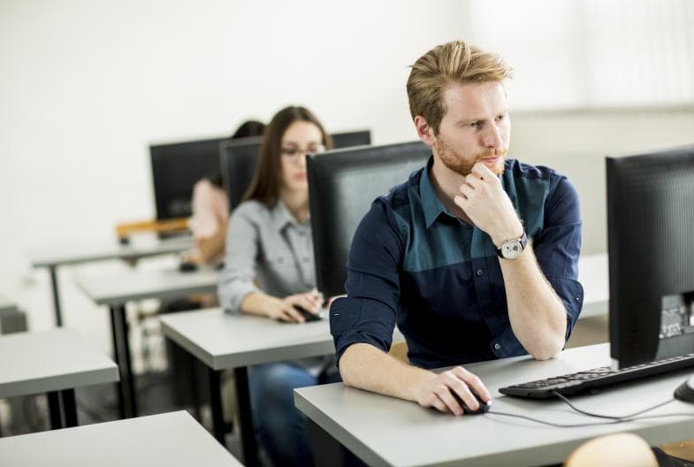 Studenter ved PCer i klasserom